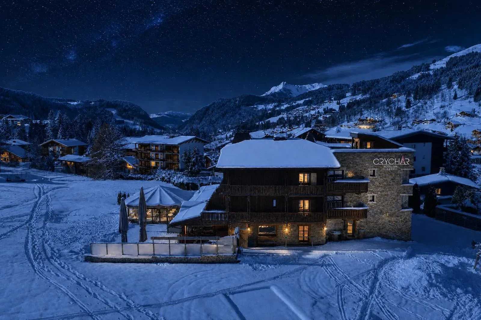 Espacio representativo del hotel: Alojamientos de montaña cubiertos de nieve brillan bajo un cielo estrellado.