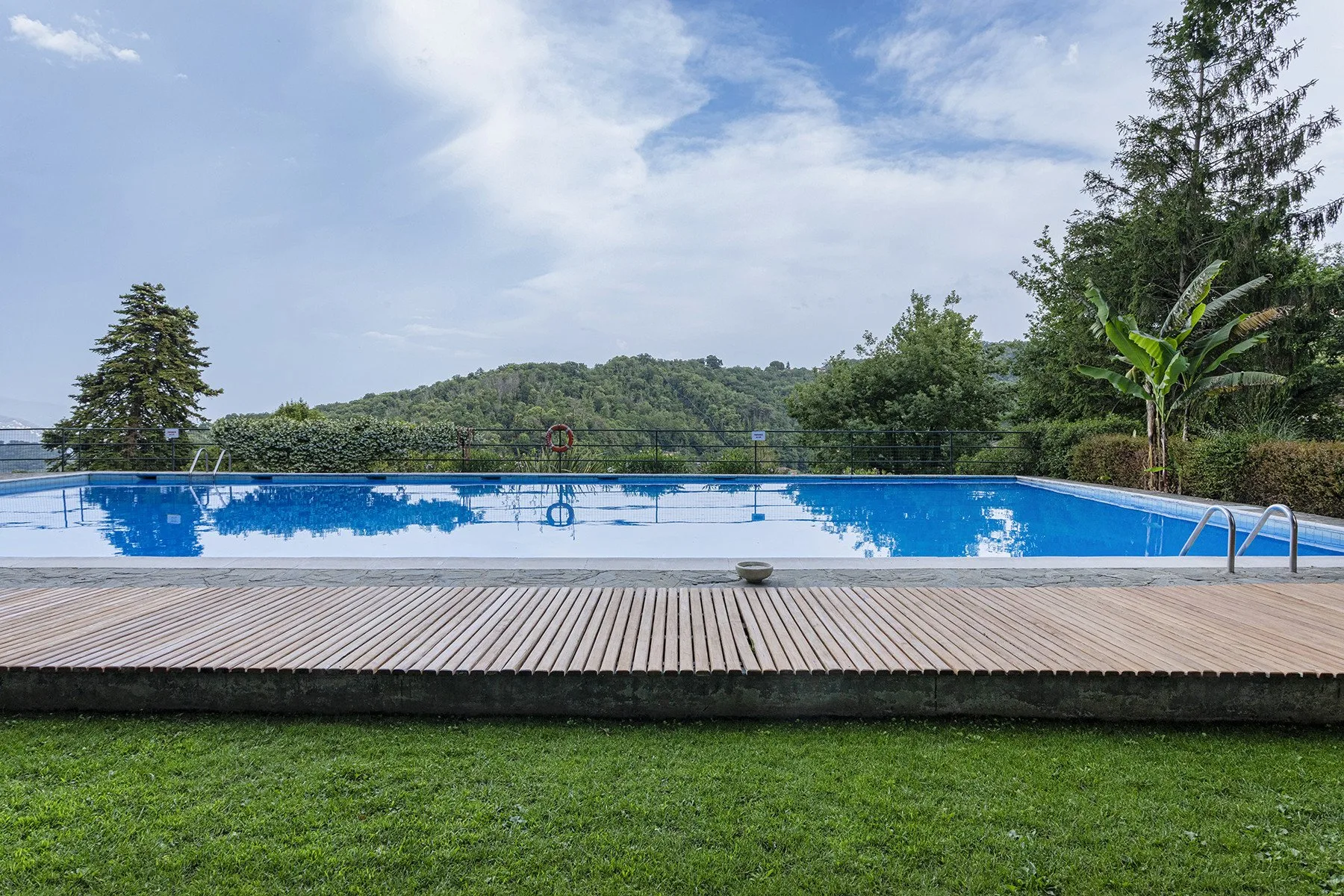 Shared amenity: An outdoor swimming pool sits beside a wooden deck and green lawn.