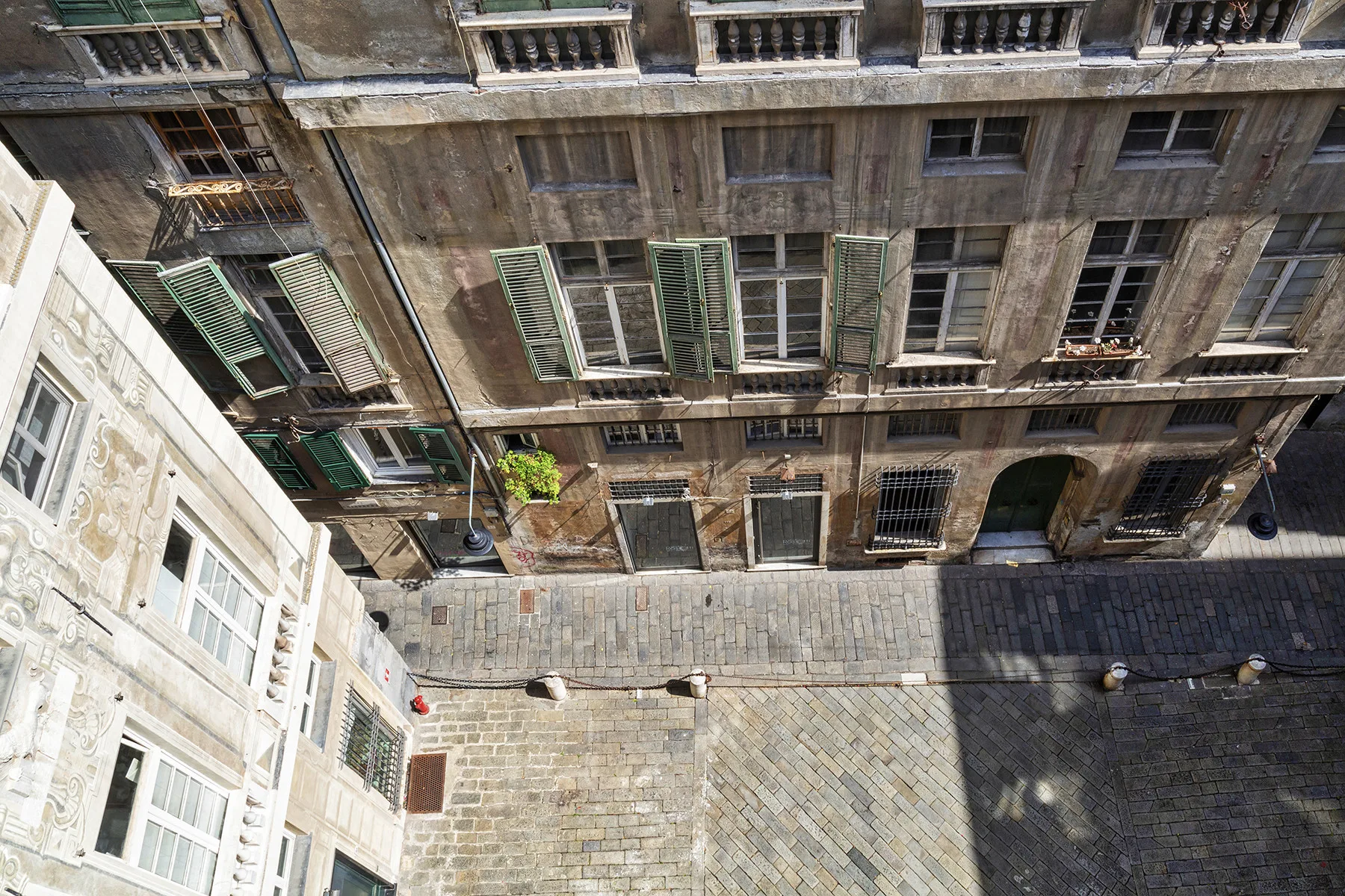 Un patio pavimentado está rodeado de edificios antiguos con ventanas con contraventanas.