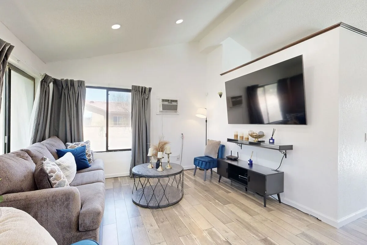 Una sala luminosa con asientos, una mesa de centro y un televisor montado en la pared.