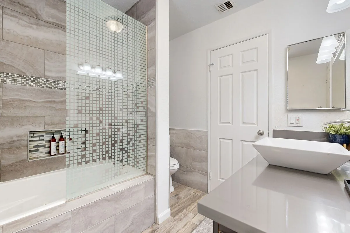 Un baño con ducha de vidrio, lavabo blanco y espejo.