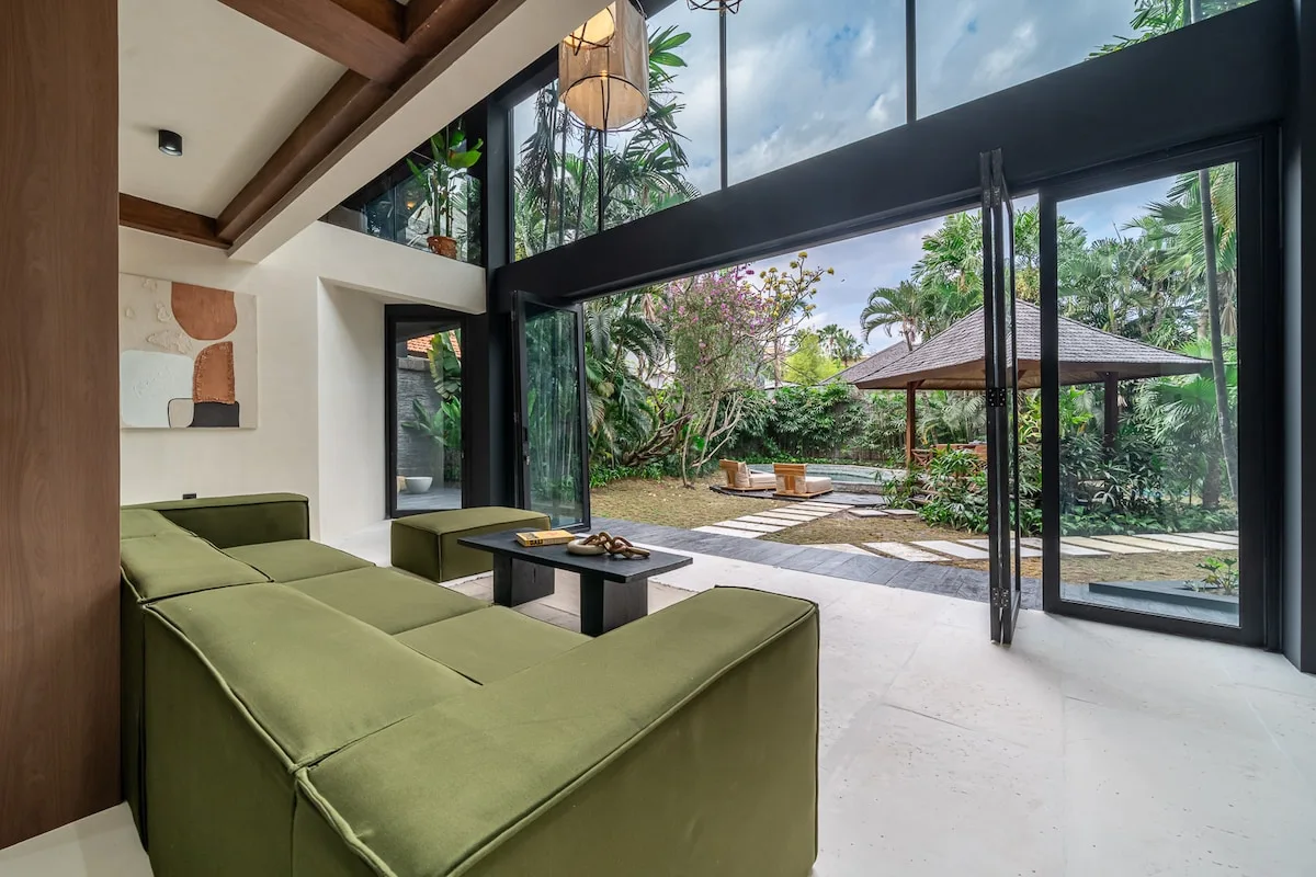 A living room opens onto a garden patio through tall glass doors.