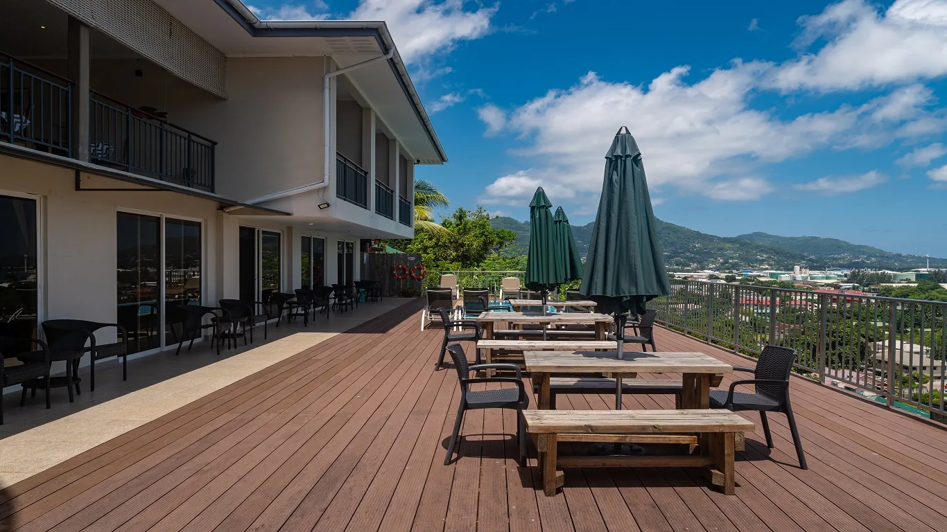Representative hotel space: An outdoor dining deck with tables and closed umbrellas overlooks a hillside landscape.