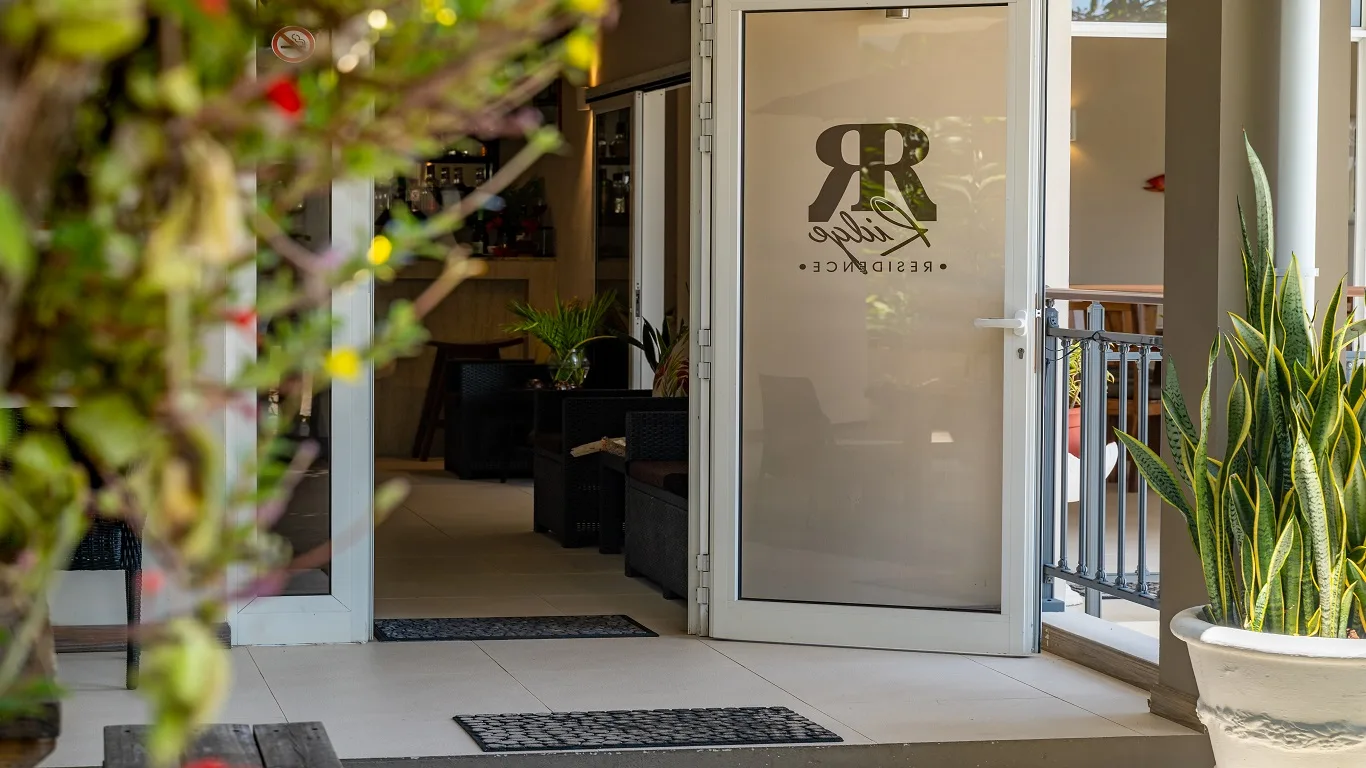 Representative hotel space: A glass entrance opens onto a covered patio with seating and potted plants.