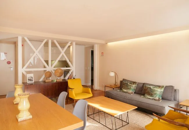 A living room with gray seating, a yellow chair, and a wooden coffee table.