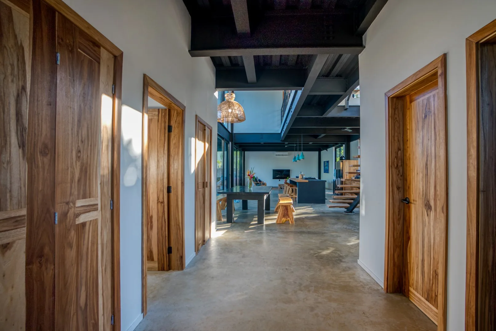 A hallway with wooden doors opens onto a bright living area.