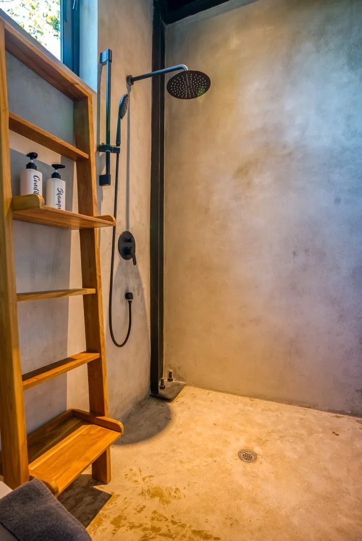 A walk-in shower with a rainfall showerhead and built-in wooden shelving.