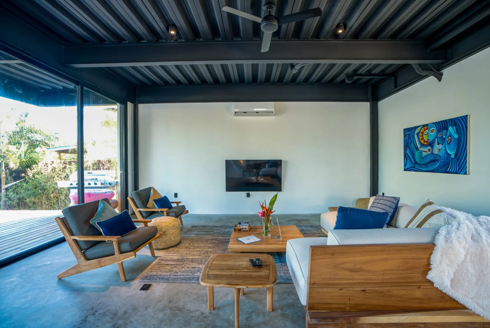 A living room with seating around a wooden coffee table and a wall-mounted television.