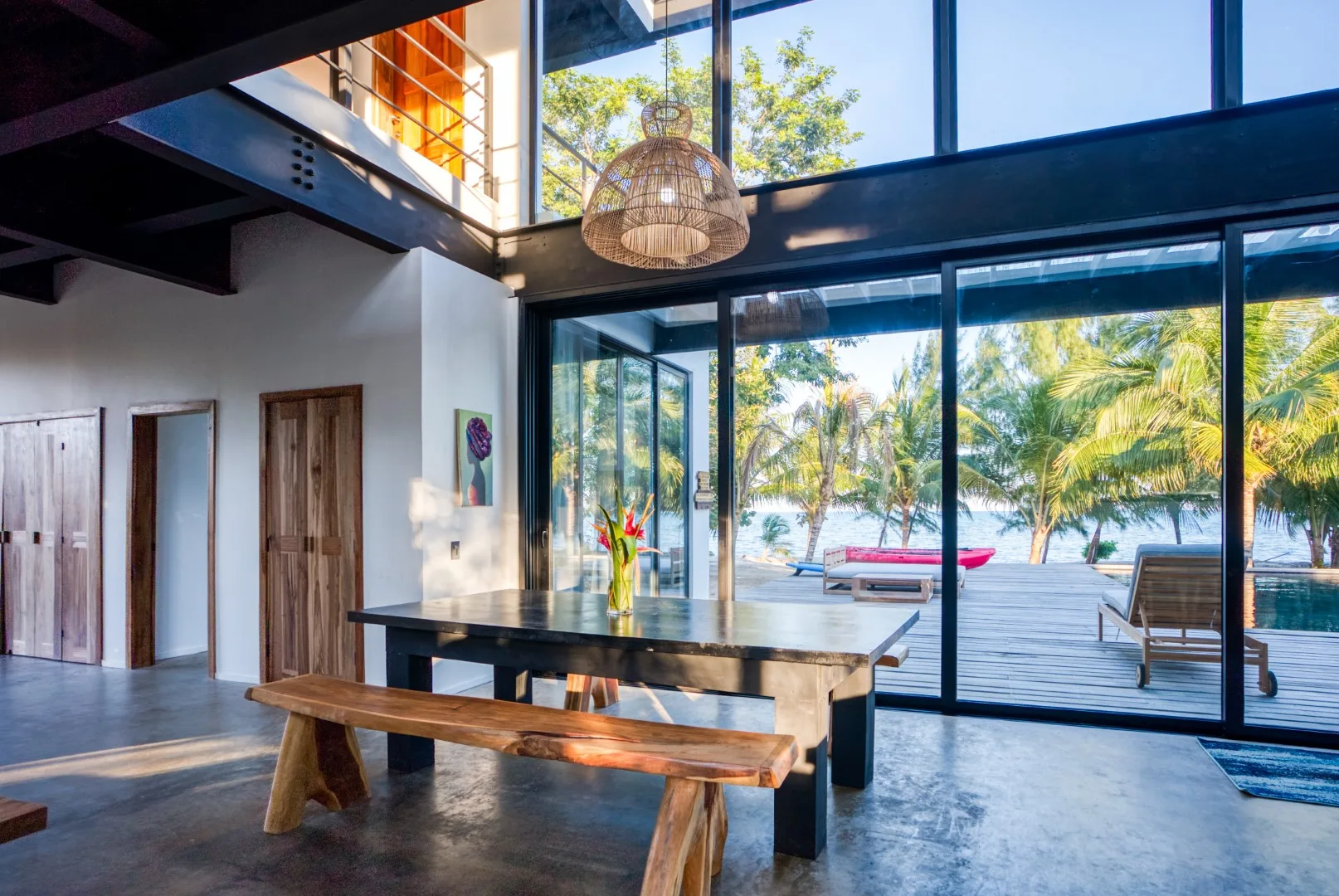 A dining area opens through glass doors onto a palm-lined waterfront deck.