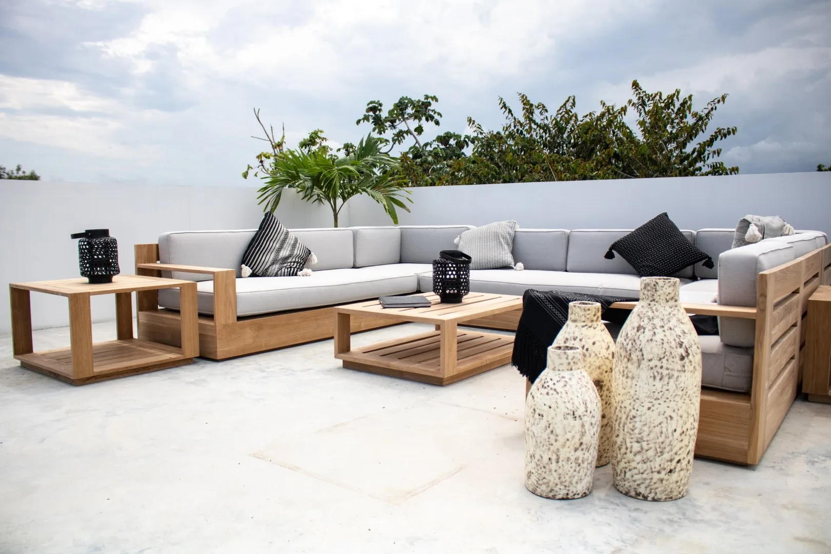 An outdoor lounge area with sectional seating and low wooden tables.
