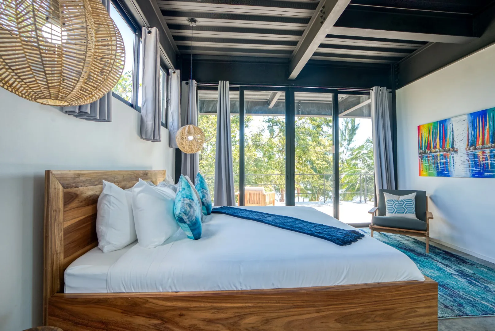 A bedroom with a large bed and sliding glass doors overlooking greenery.