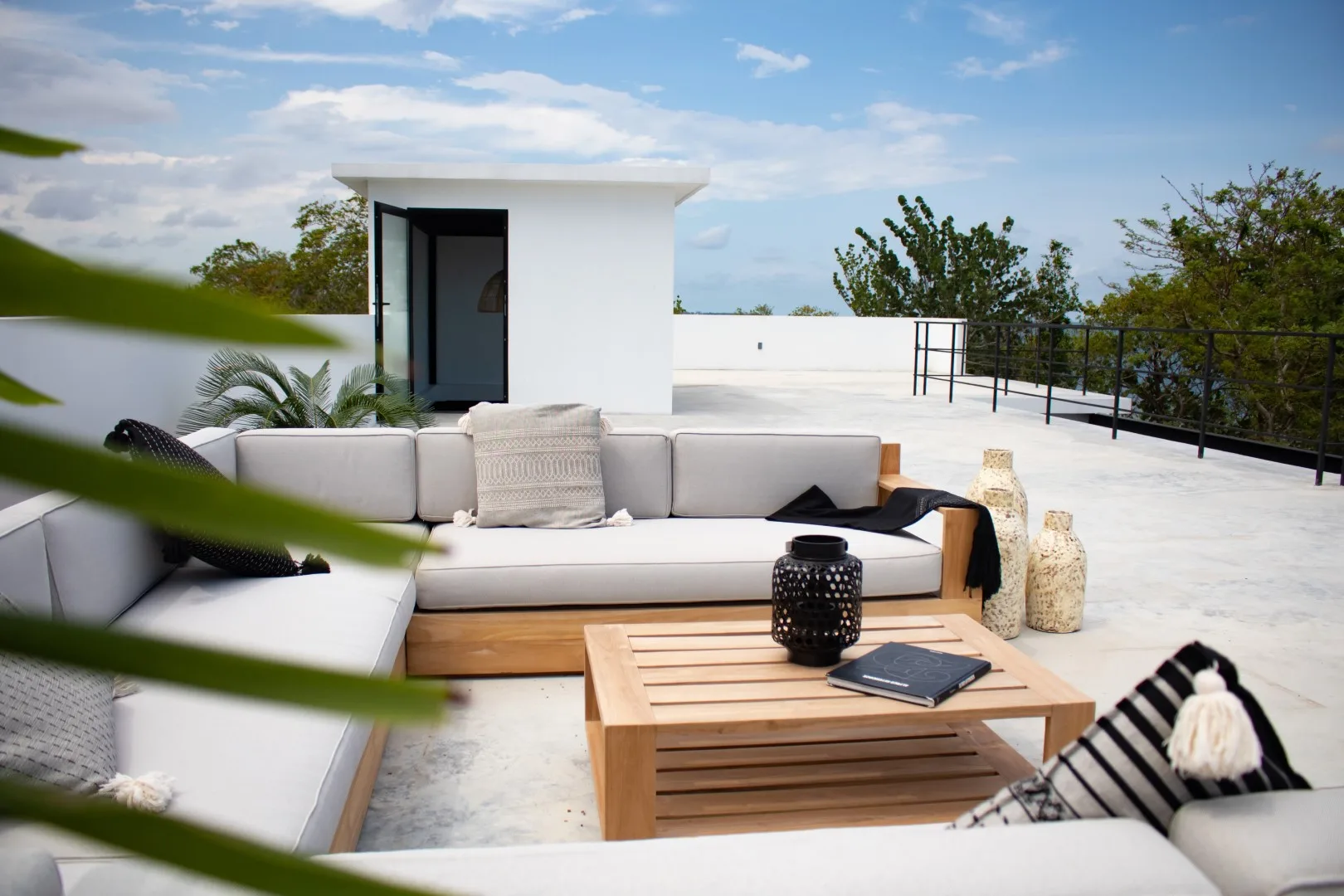 An outdoor rooftop lounge with cushioned seating and a wooden coffee table.