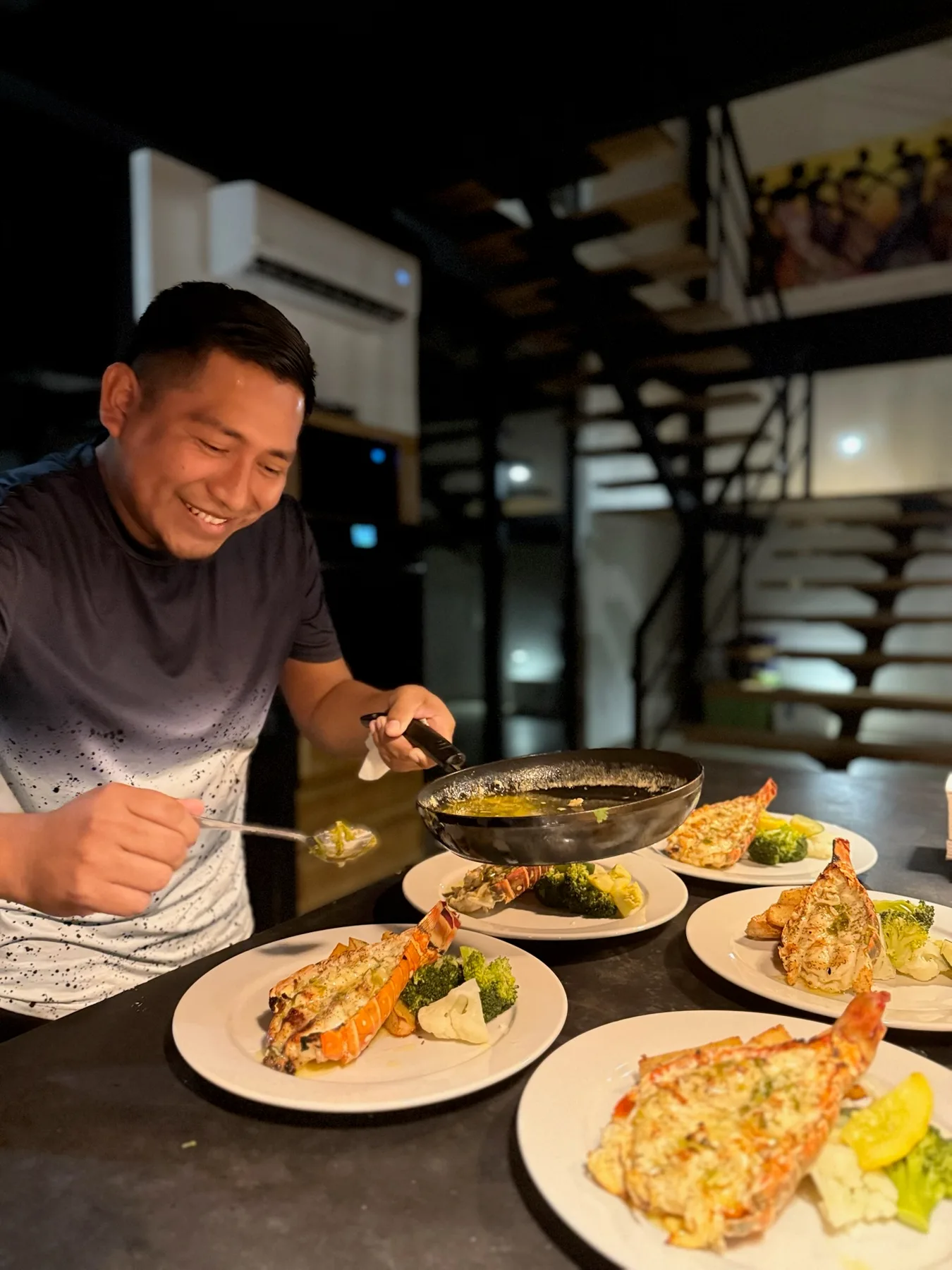 A man serves plated food at a counter in a warmly lit restaurant.