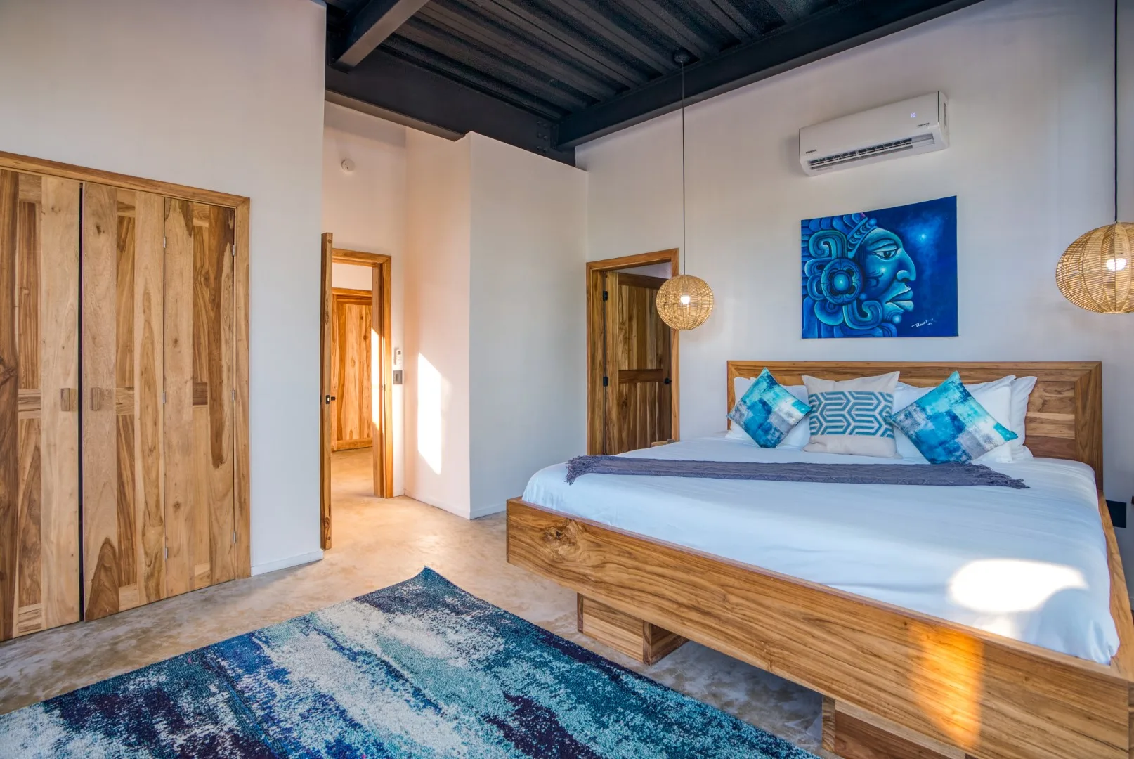 A bedroom with a wooden bed, blue bedding, and a patterned rug.