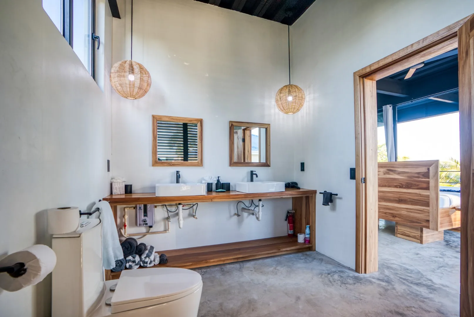 A bathroom with a long counter and two sinks, opening onto a covered outdoor area.