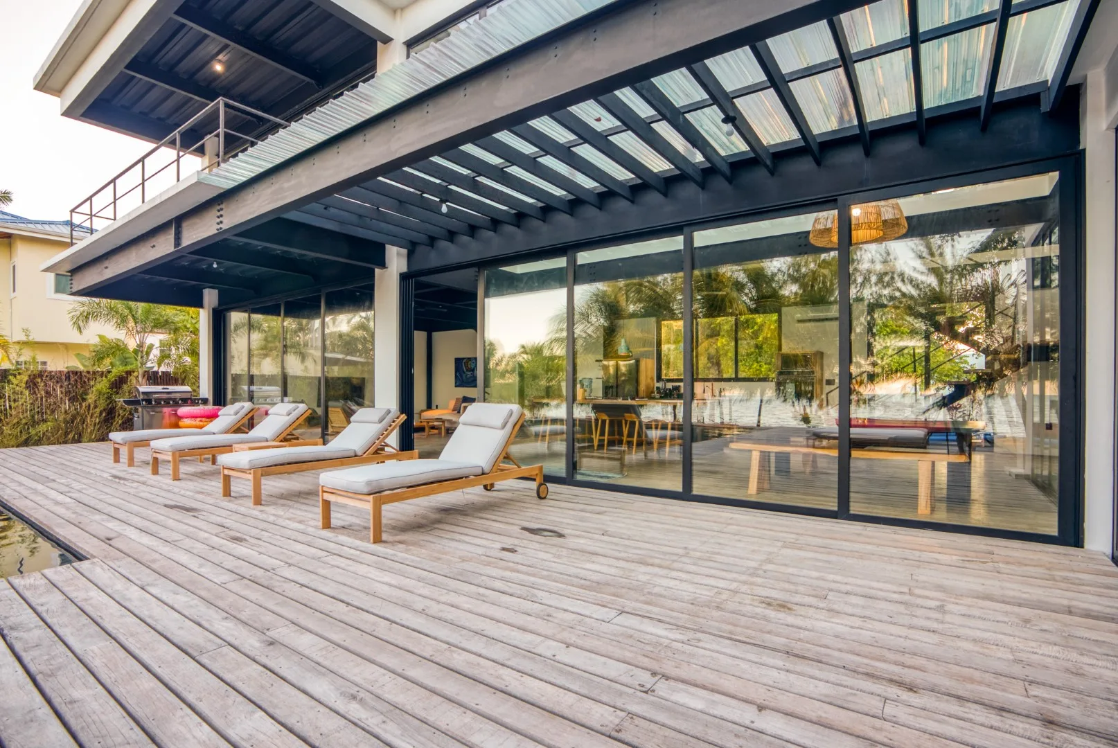 A patio with lounge seating sits outside a glass-walled living area.