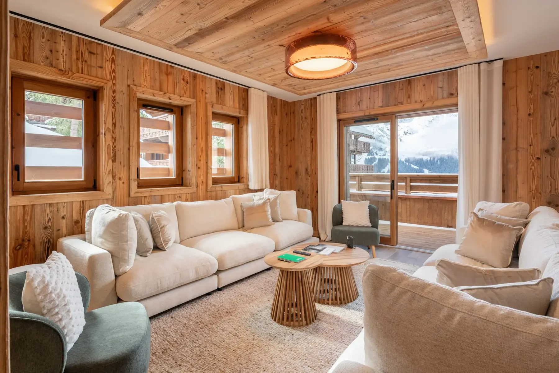 Una sala de estar revestida de madera con asientos claros y una mesa de centro redonda.