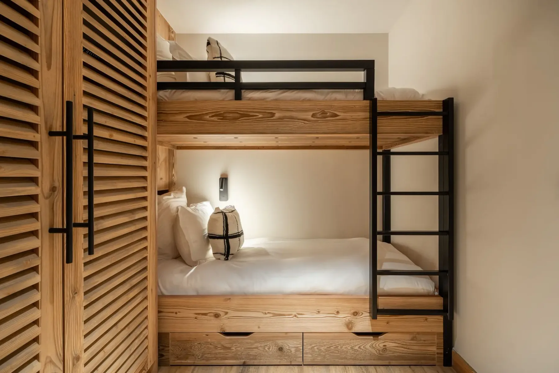 Una zona compacta para dormir cuenta con literas empotradas de madera y barandillas metálicas negras.