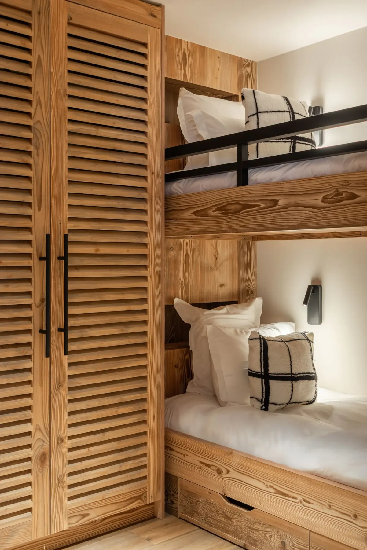 Un dormitorio revestido de madera con literas y ropa de cama blanca.