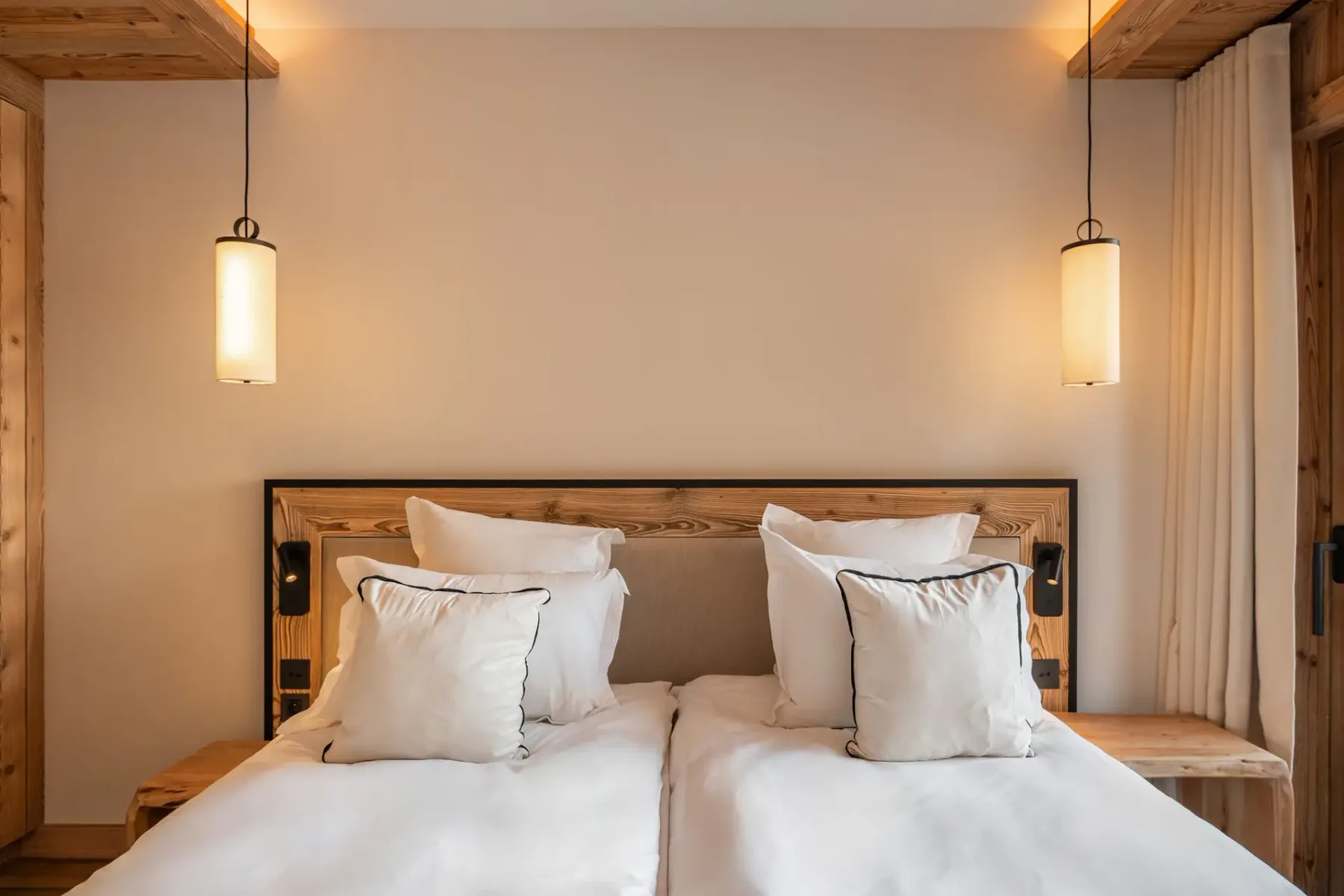 Un dormitorio con dos camas y lámparas colgantes junto a una ventana con cortinas.