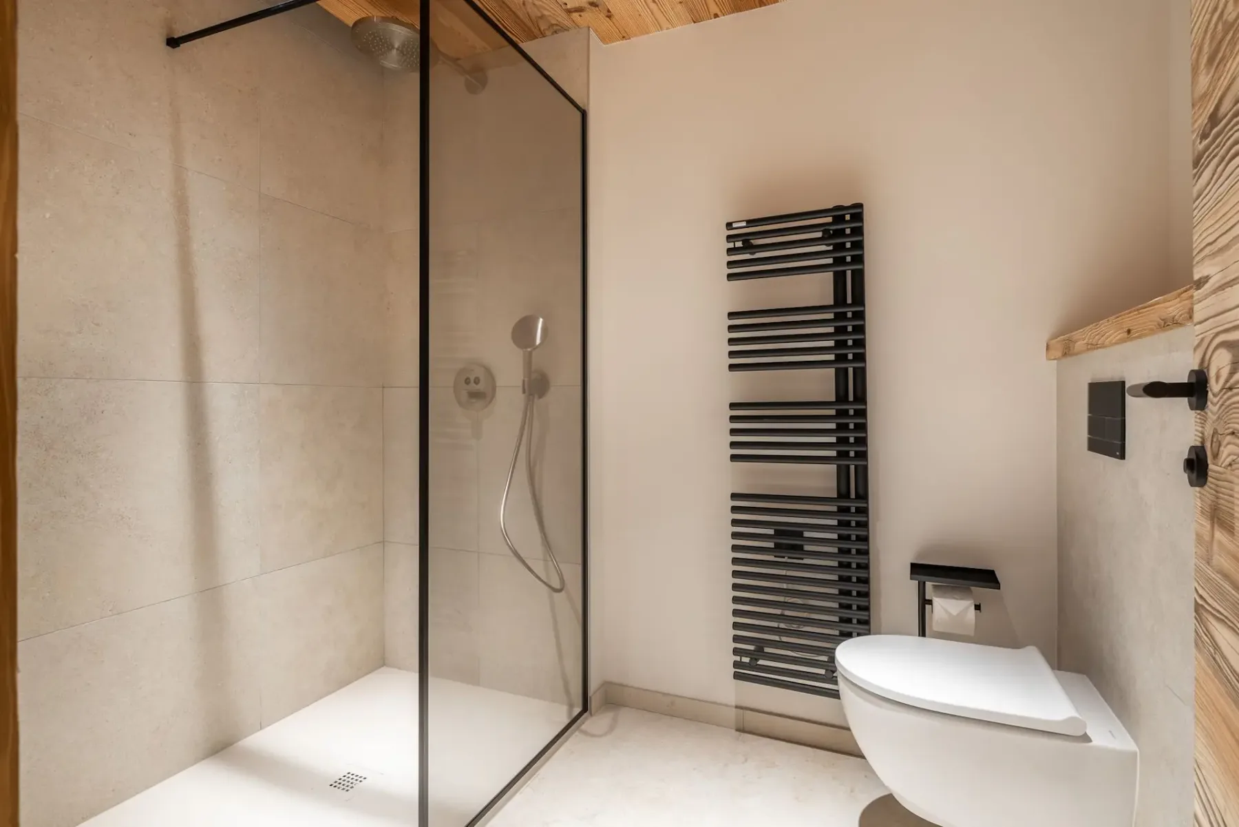 Un baño con una ducha de vidrio y un radiador toallero de pared.