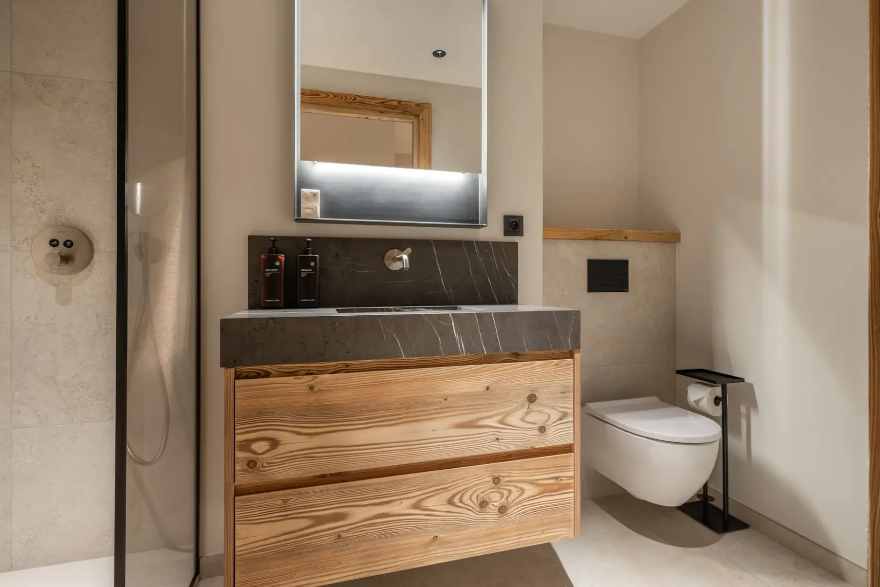Un baño con mueble de lavabo de frente de madera, espejo y sanitario.