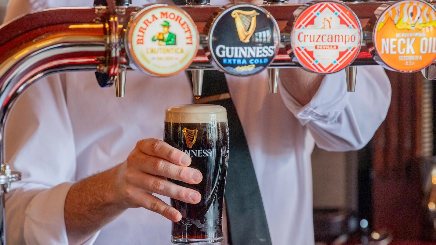 Espacio representativo del hotel: Un camarero sostiene una cerveza oscura recién servida bajo una fila de grifos.