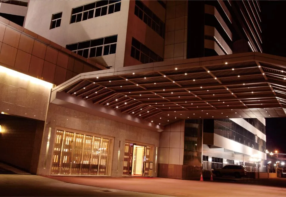 Representative hotel space: A modern building entrance is illuminated beneath a broad canopy at night.