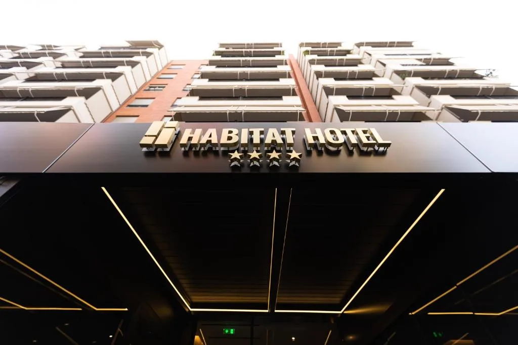 Espacio representativo del hotel: Exterior del hotel con el letrero HABIFAT HOTEL sobre una marquesina oscura.