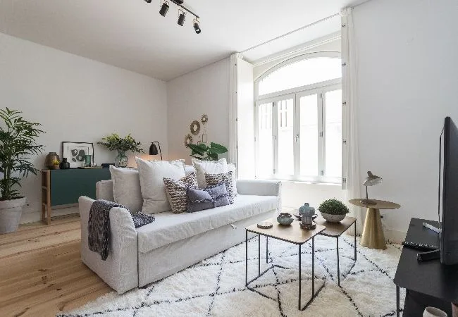 A bright living room with a white sofa and large windows.