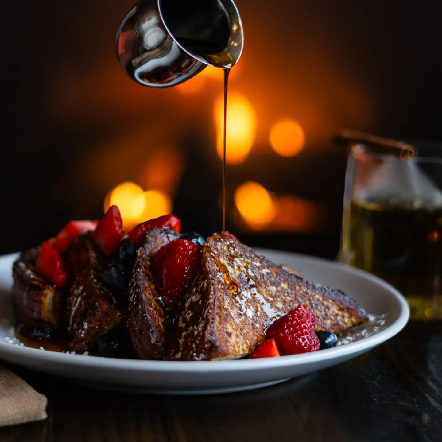 Espacio representativo del hotel: Un postre con frutos rojos en un plato recibe un chorrito de sirope en una mesa.
