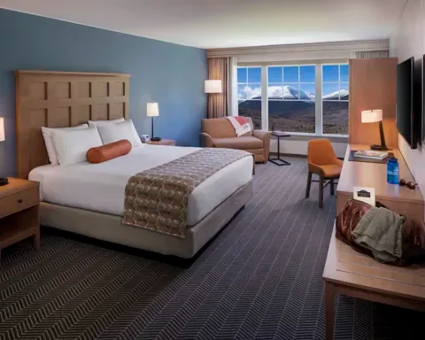 Espacio representativo del hotel: Un dormitorio de hotel con cama, escritorio y una ventana amplia con vista a las montañas.