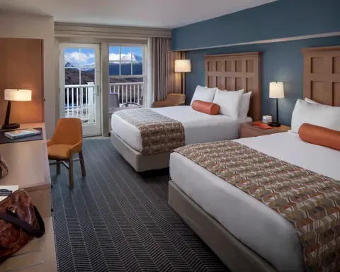 Espacio representativo del hotel: Un dormitorio de hotel con dos camas y un balcón visible a través de las puertas de vidrio.