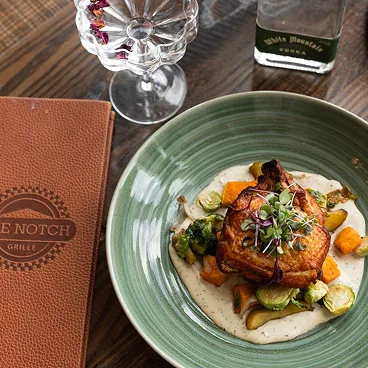 Espacio representativo del hotel: Un plato con verduras está sobre una mesa de restaurante junto a un menú y cristalería.