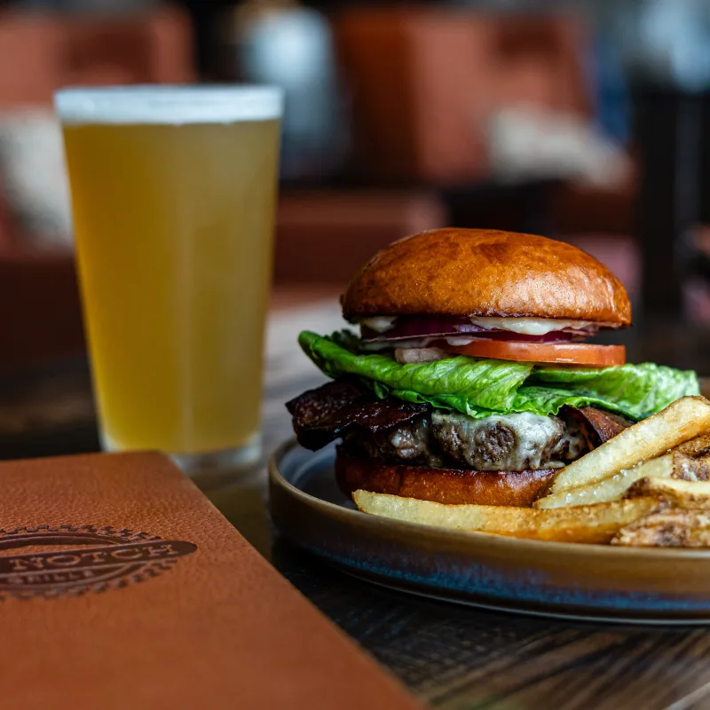 Espacio representativo del hotel: Una hamburguesa con lechuga y papas fritas está junto a un vaso de cerveza.