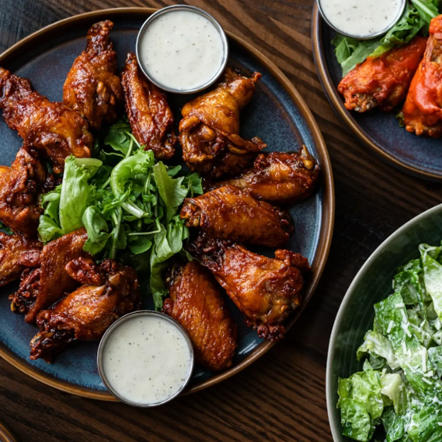 Espacio representativo del hotel: Platos de alitas de pollo glaseadas con salsa para untar y ensalada verde.