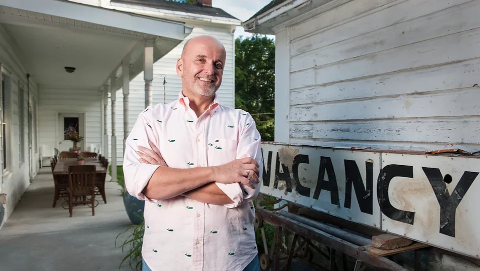 Representative hotel space: A man stands beside a weathered sign along a covered outdoor walkway.