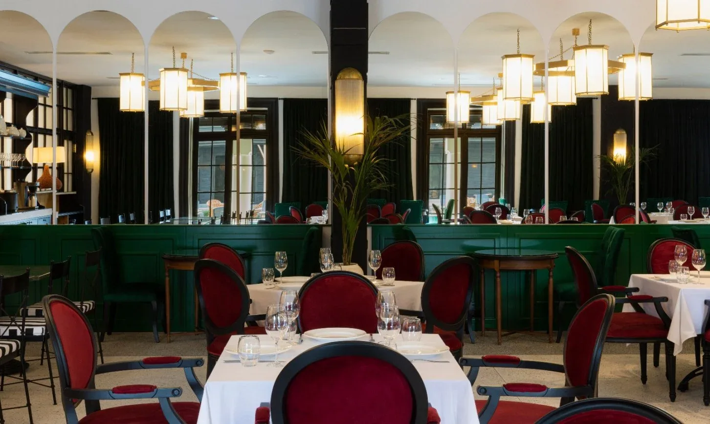 Representative hotel space: A dining room with set tables, red seating, and hanging lights.