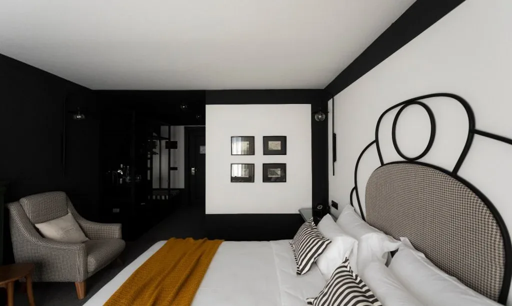 Representative hotel space: A hotel bedroom with a large bed, patterned pillows, and an armchair.