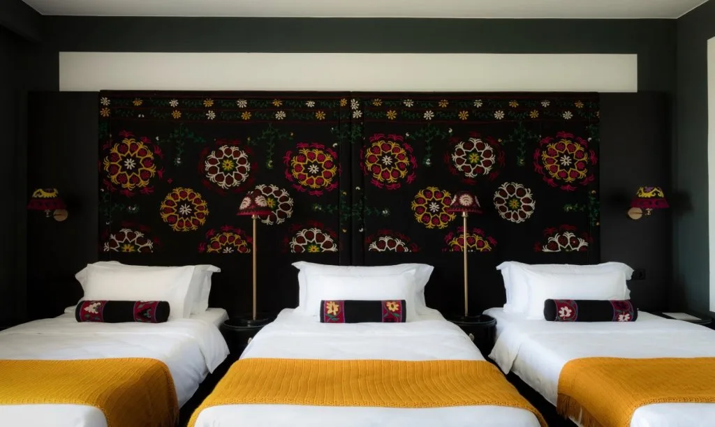 Representative hotel space: A hotel bedroom with three beds and colorful patterned wall panels.