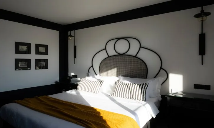 Representative hotel space: A bedroom with a large bed, striped pillows, and a decorative headboard.