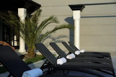 Representative hotel space: Outdoor poolside seating sits beside a palm and a light-colored wall.