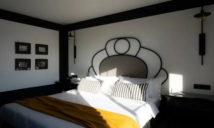 Representative hotel space: A bedroom with a bed beneath a decorative curved headboard.