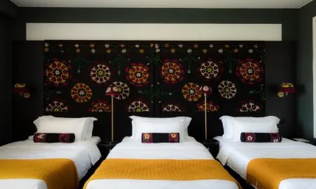Representative hotel space: A hotel bedroom with three beds arranged against a patterned wall.