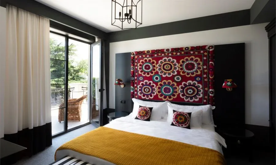 Representative hotel space: A bedroom with a bed beneath a colorful patterned wall hanging.