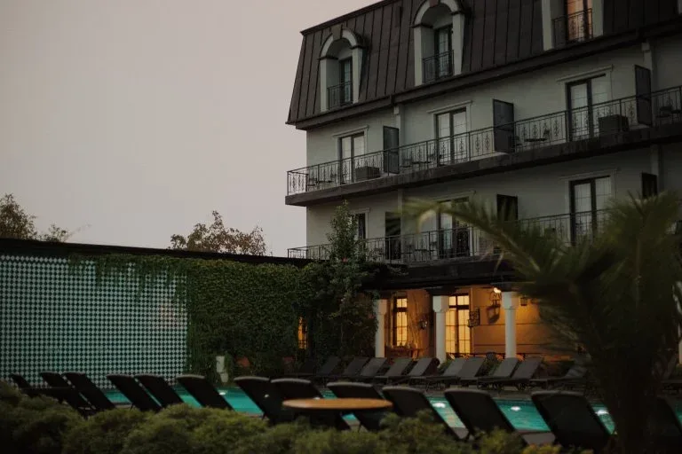 Representative hotel space: Hotel building overlooks an outdoor pool lined with lounge seating.