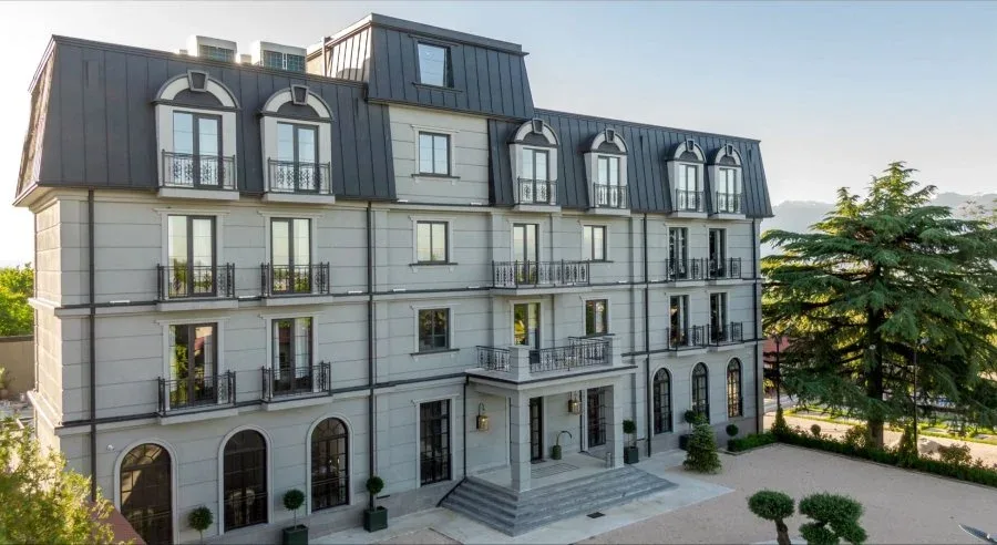 Representative hotel space: A multi-story building with rows of windows and balconies beside landscaped grounds.