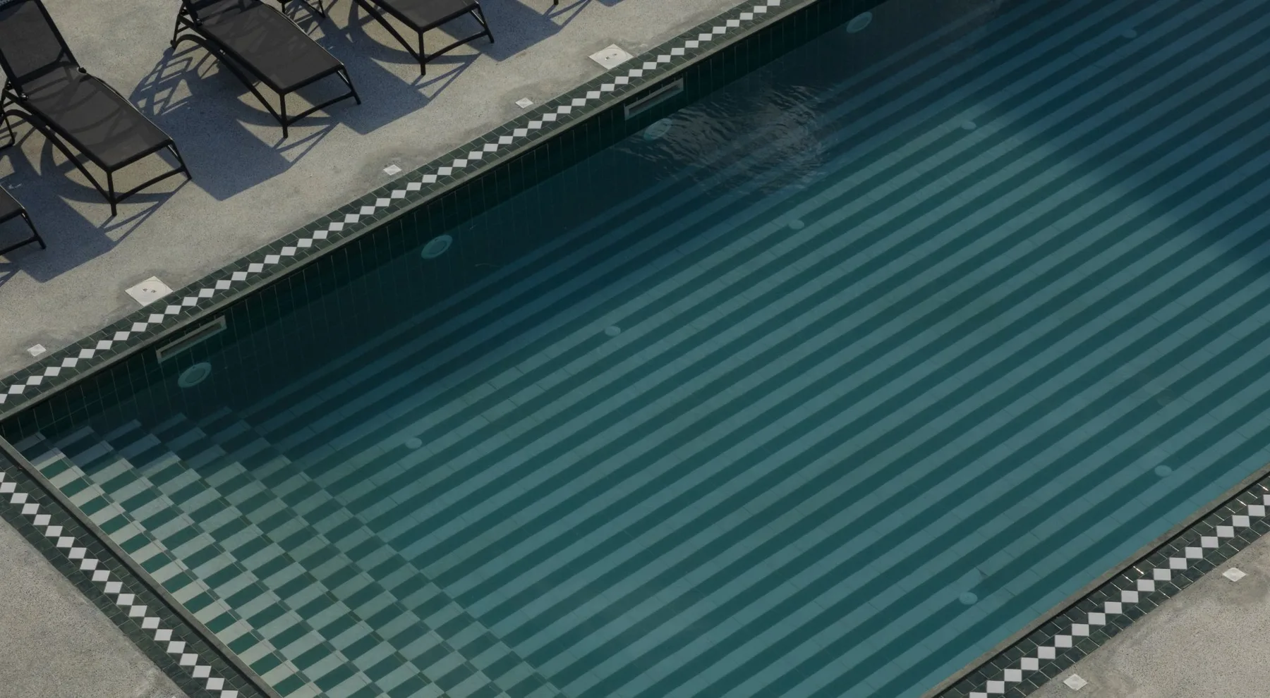 Representative hotel space: An outdoor swimming pool with striped lane markings and loungers along the deck.