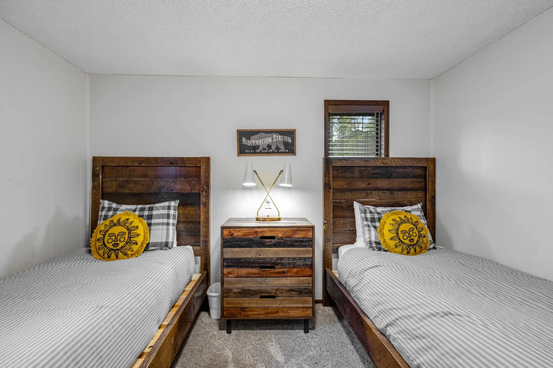 A bedroom with two beds and a wooden dresser between them.