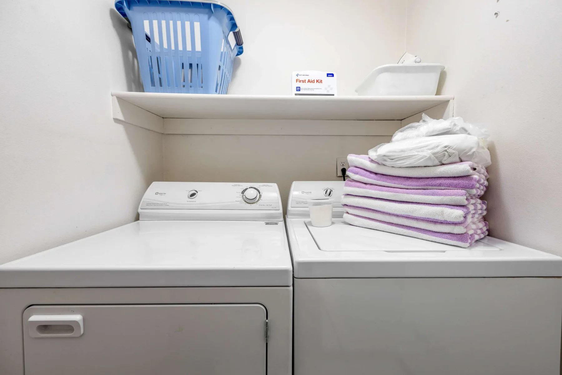 A laundry room with a washer, dryer, and folded towels.